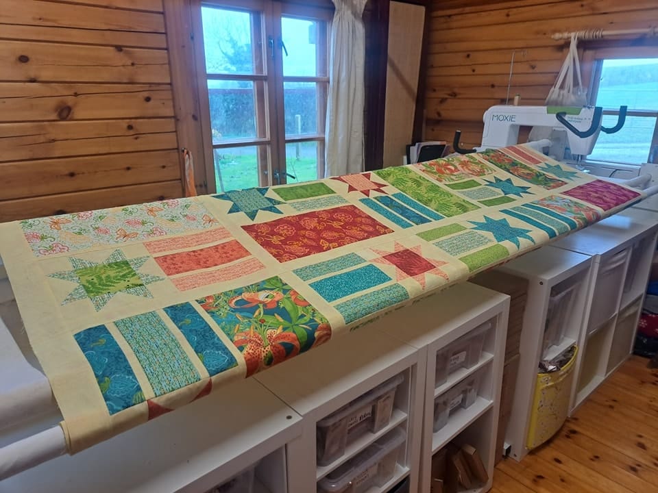 Patchwork quilt on longarm quilting machine ready for basting.