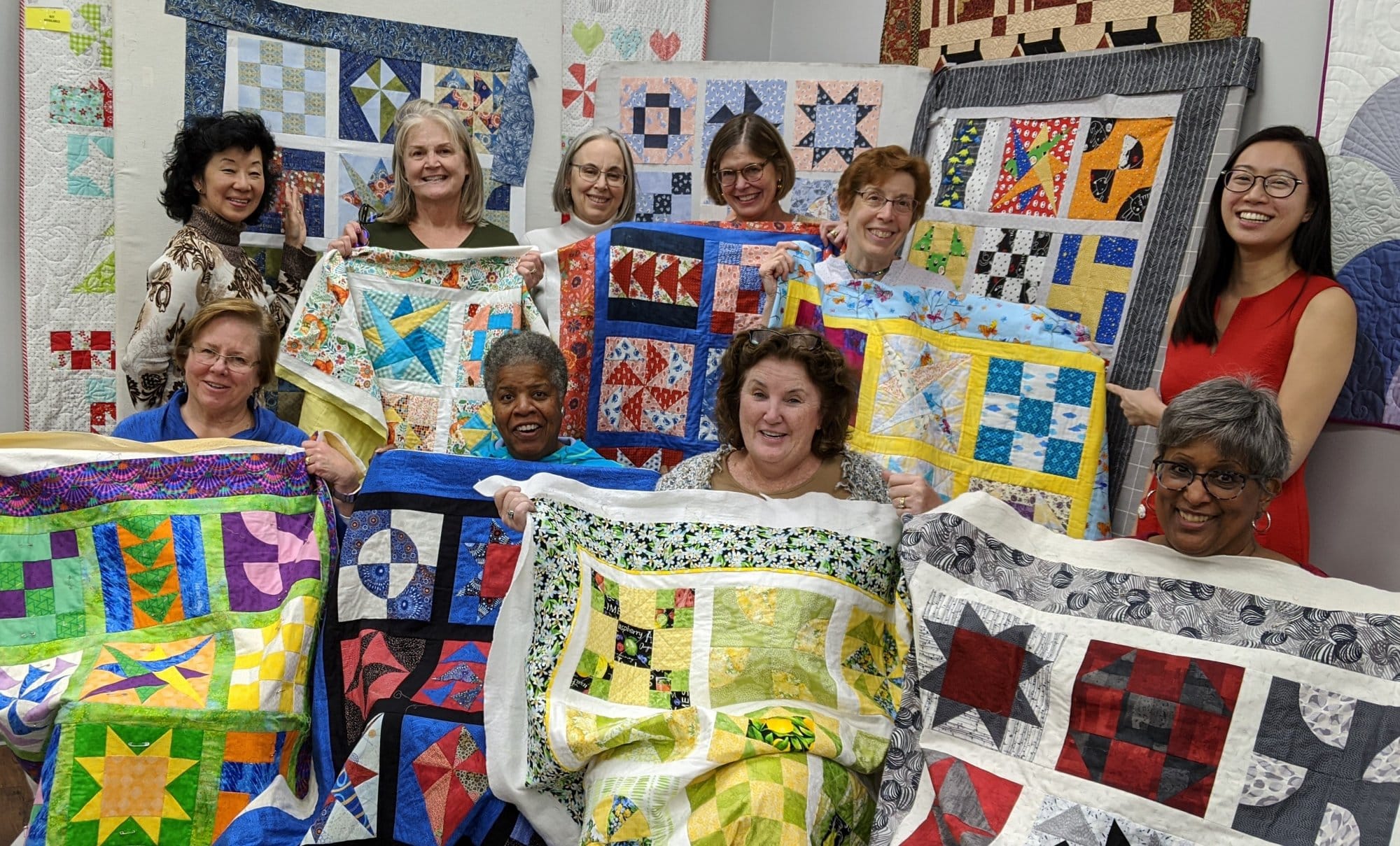 Woman displaying crafted quilts at Nifty Needles workshop.