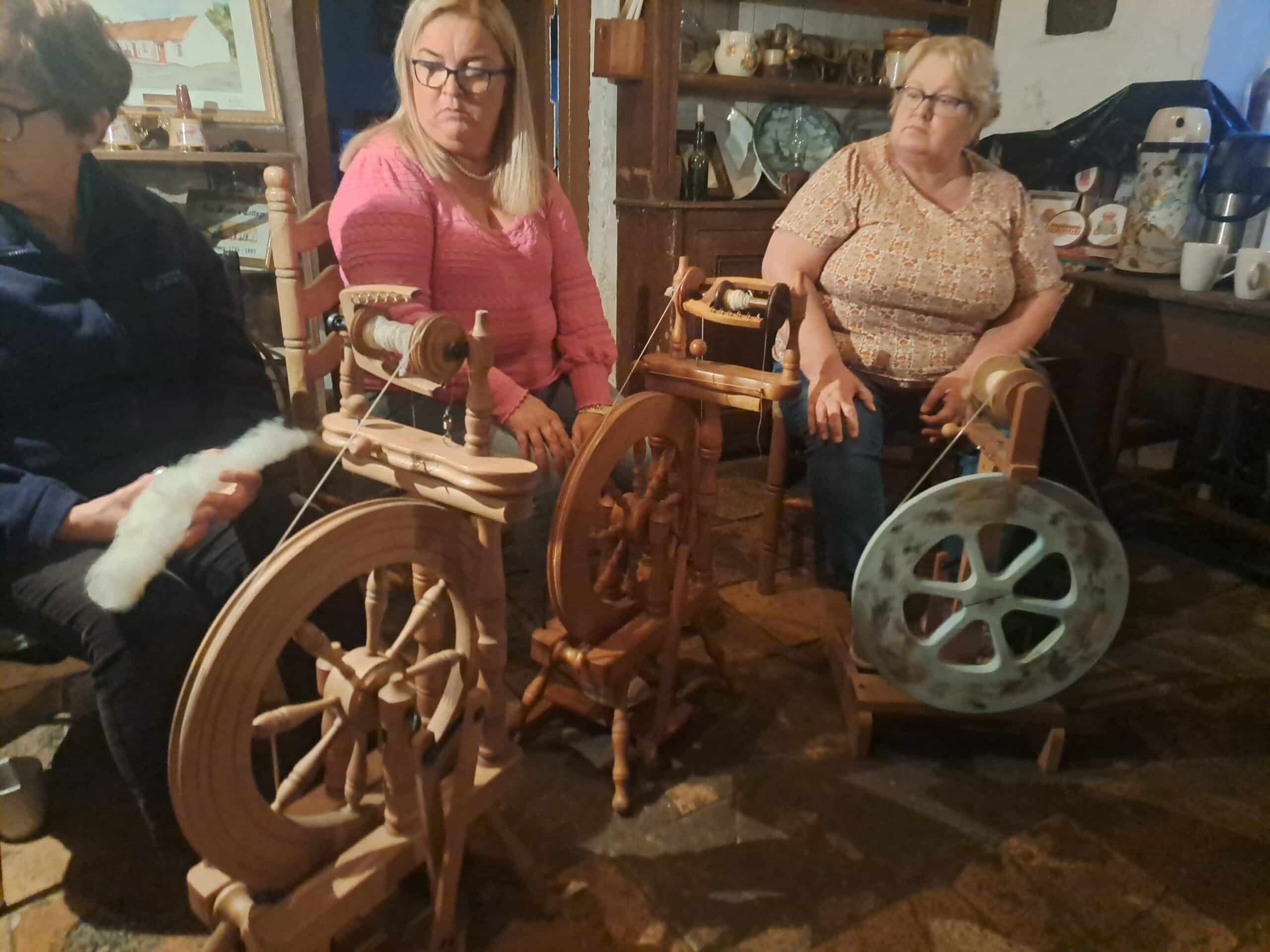 Women spinning yarn using spinning wheels during a workshop.